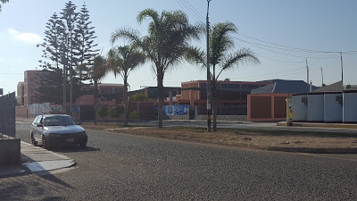 A photo taken from the distance that shows Colegio Miguel Pro, next to the local marketplace. A taxi waits at the curb. 